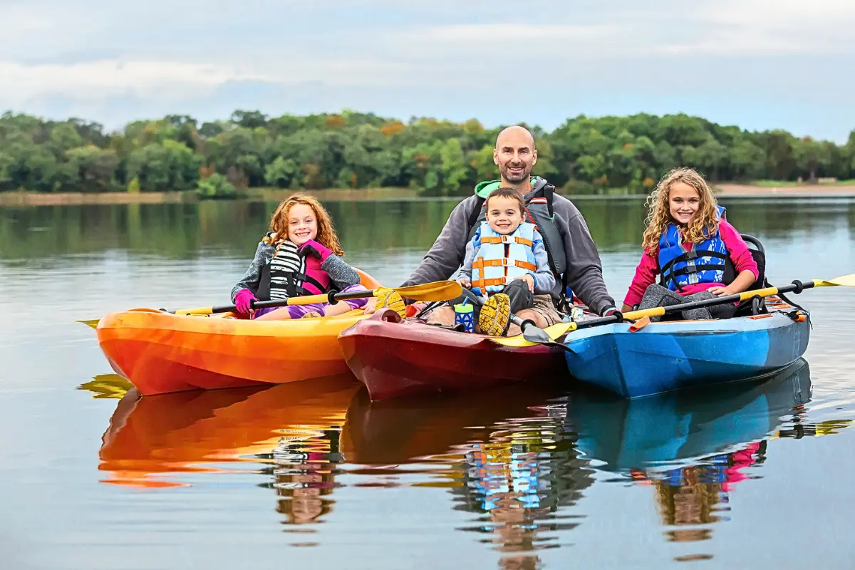 Family kayaking on a lake during an affordable family vacation in the Northeast.